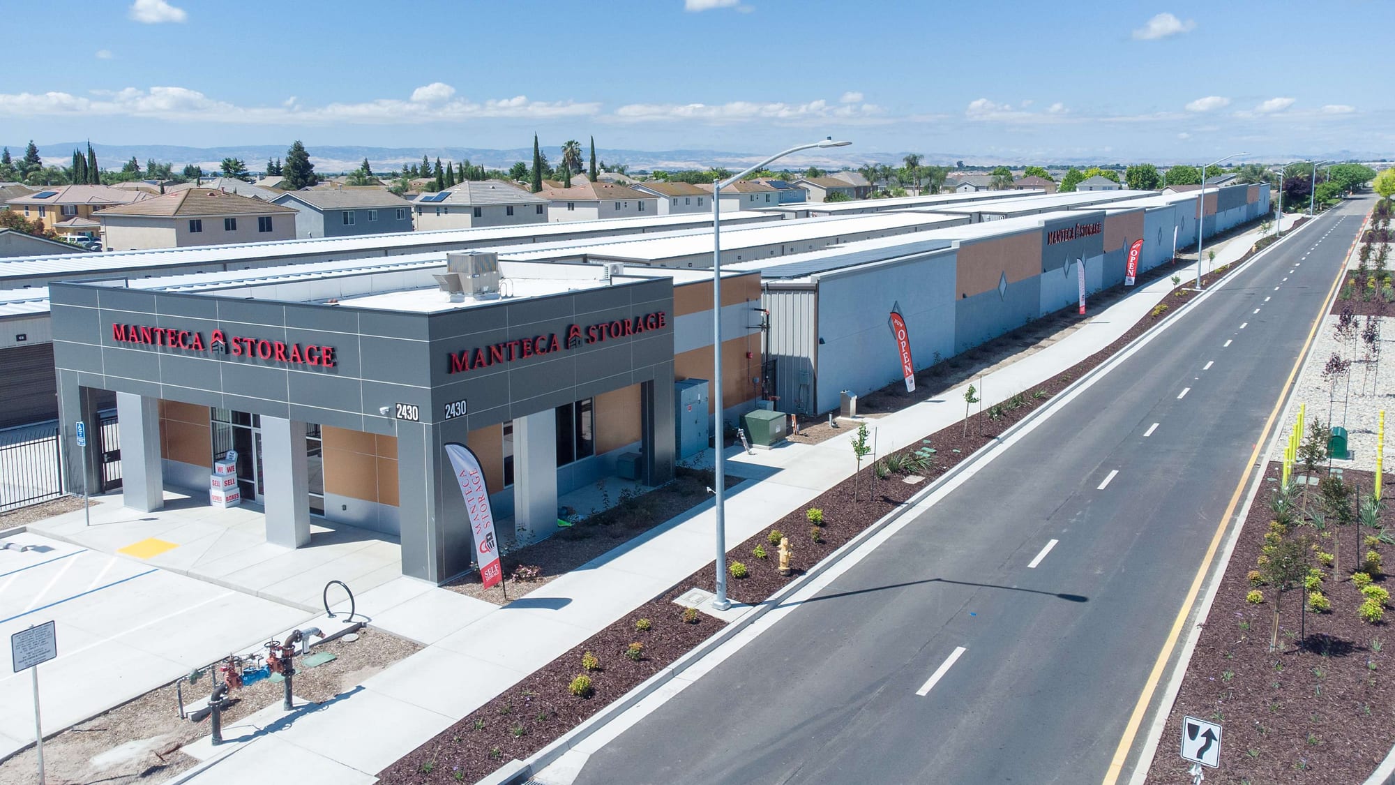 Manteca Storage seen from above along W Atherton Dr, with NOW OPEN banners at the street frontage