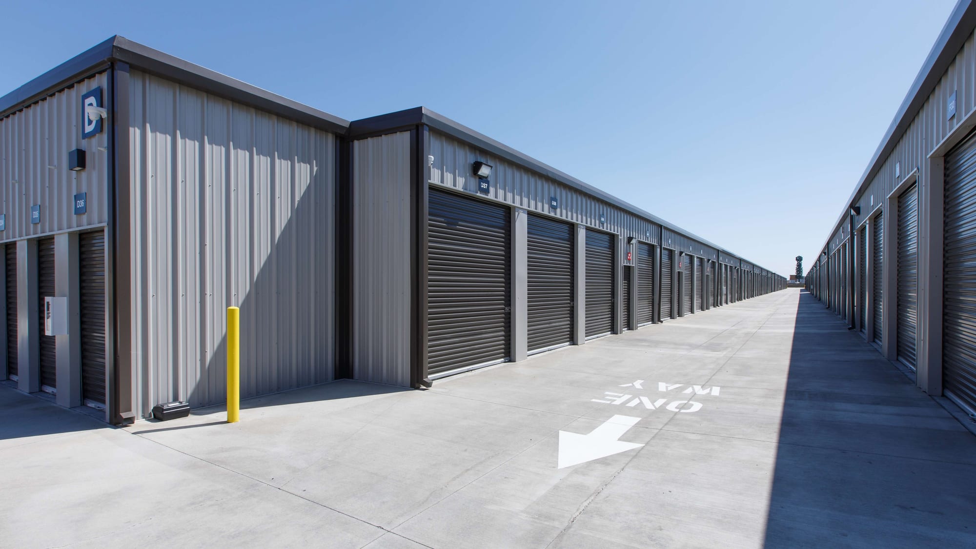 Building D at Manteca Storage, its drive-up units lit by exterior floodlights and covered by a corner camera