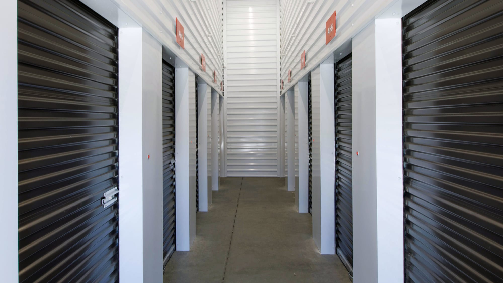 A clean, well-lit indoor corridor of numbered interior storage units at Manteca Storage
